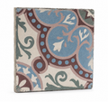 Angled view of an antique French floral cement tile showing its patterned face, aged edges, and solid construction.
