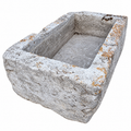 A rectangular stone trough or basin with a rough, weathered texture and natural orange lichen growth, isolated on a white background.